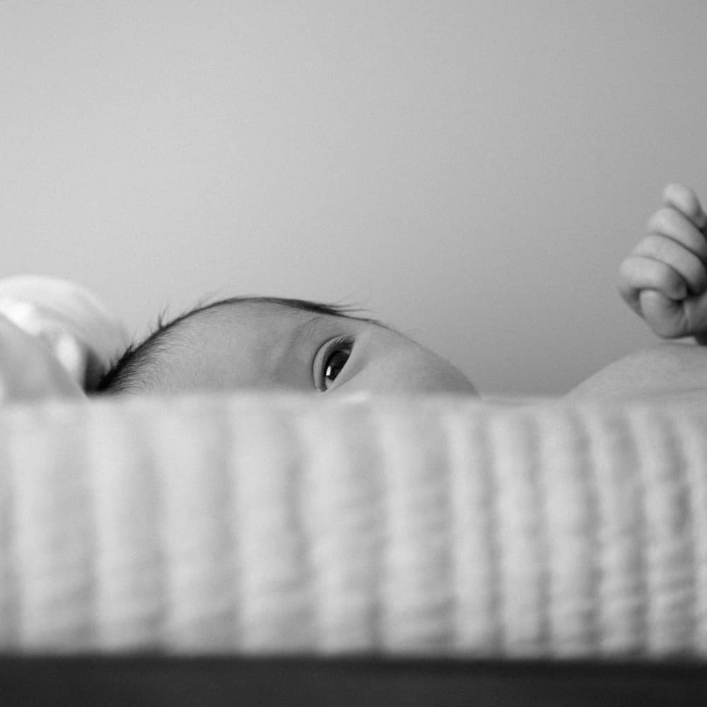 Image shows a baby with a blanket in black and white