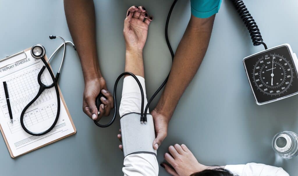 Image shows arms of medical doctor giving blood pressure test to a patient from above