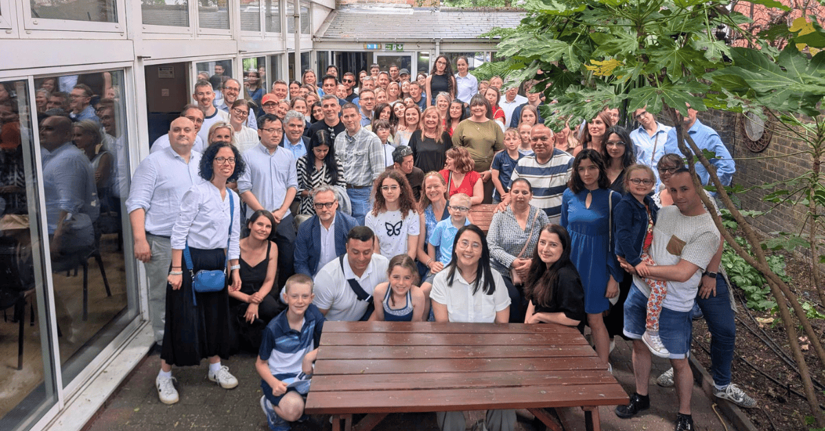Large group picture with attendees of all ages waving their hands in the air and smiling.