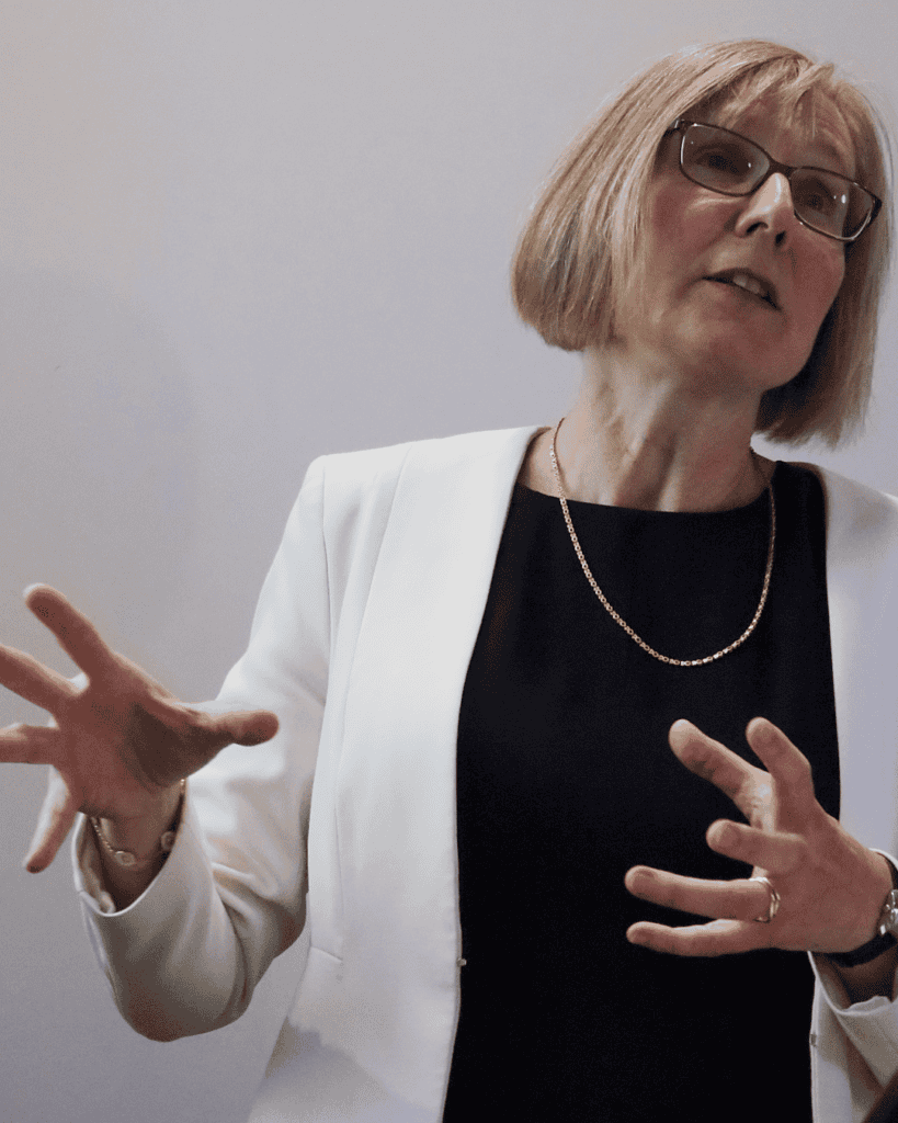 Close-up of a speaker gesturing towards presentation slides during an inaugural lecture.